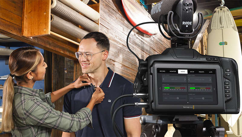 woman attaching mic to confident man's shirt